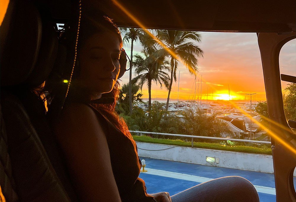 Passageira contemplando o pôr do sol de dentro do helicóptero
